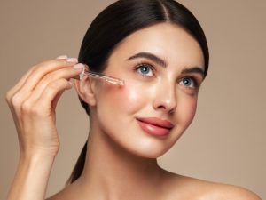 Young beautiful woman applying face serum