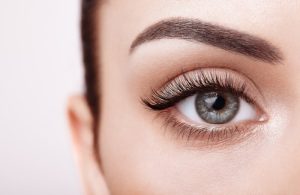 Close-up of a blue-grey eye highlighting natural eyelashes and eyebrow, showcasing eye shape.