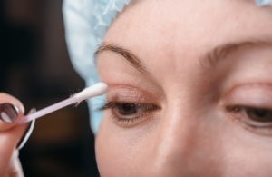 Close-up of a person’s eye showing eyelid anatomy during cleaning with a cotton swab.