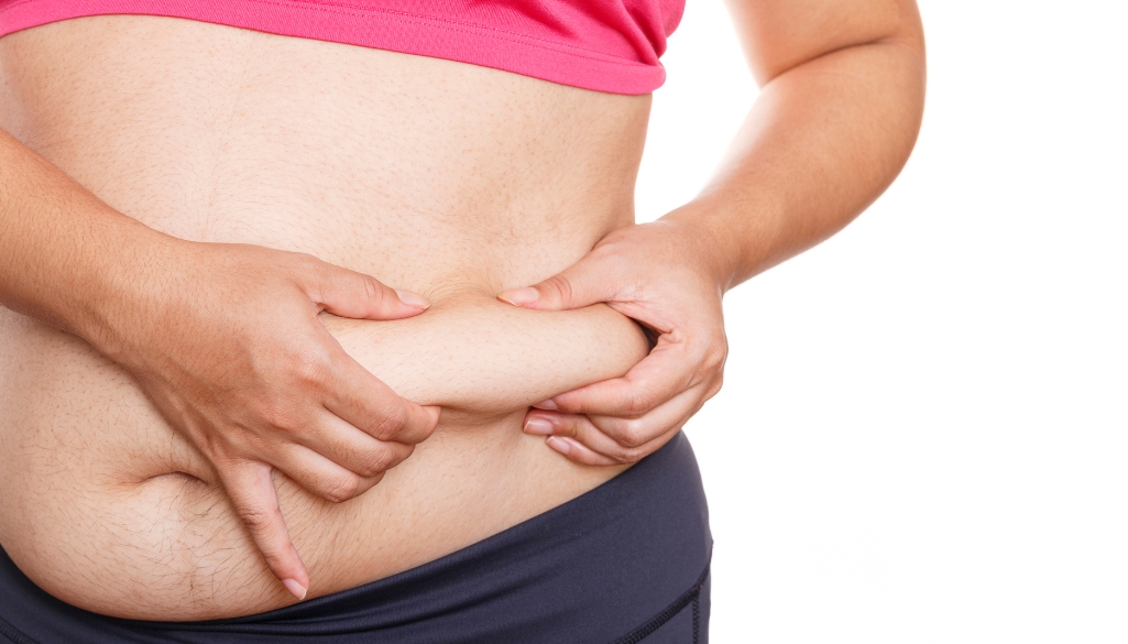 Person pinching abdominal fat, showing a visible muffin top, often targeted in treatments to get rid of a muffin top.