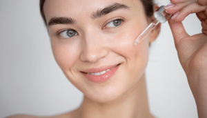 Woman applying soothing facial serum with a dropper to hydrated skin after microneedling treatment