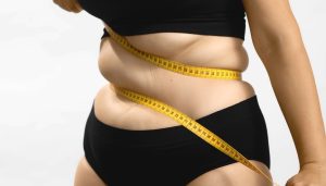 Measuring tape wrapped around the waist and lower abdomen, illustrating different types of body fat distribution.